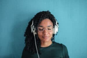 Portrait photo of smiling woman in black top and glasses wearing white headphones